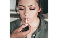 Image A hand putting on lip gloss on somone elses lips.